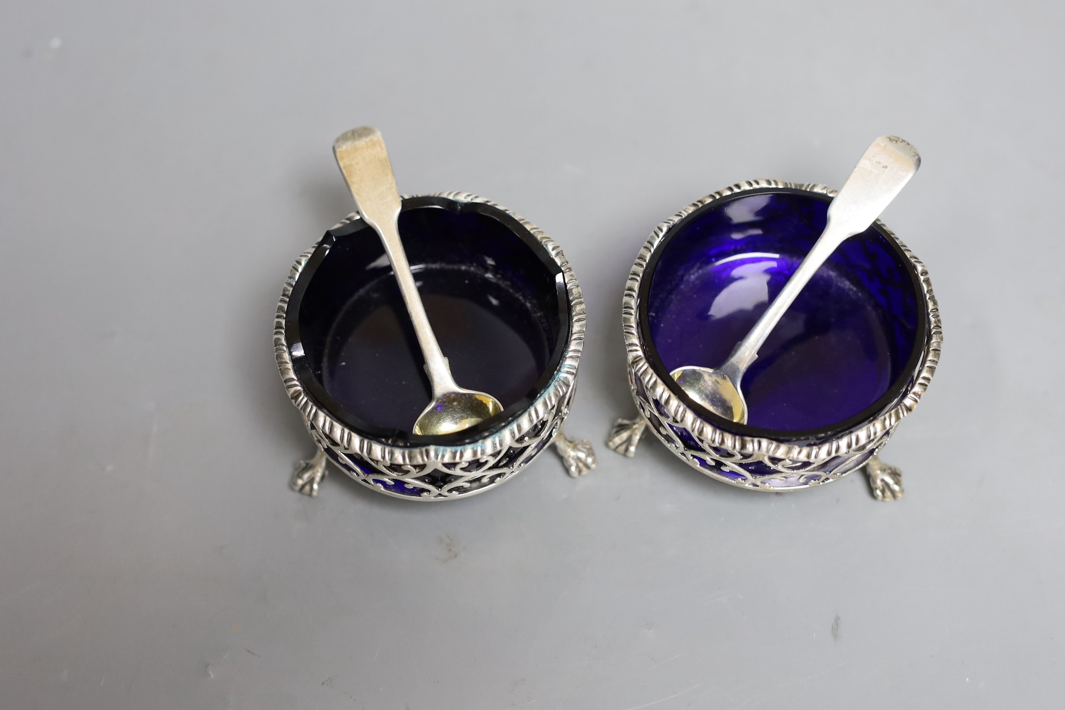 A pair of George III pierced silver circular salts, London, 1764, 79mm, with two associated spoons.